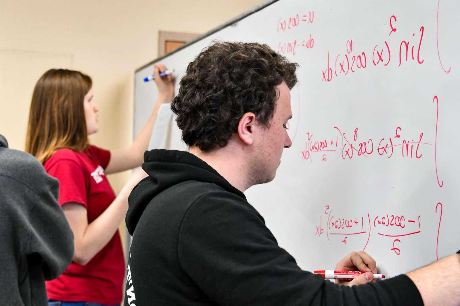 students workng on calculus at a whiteboard